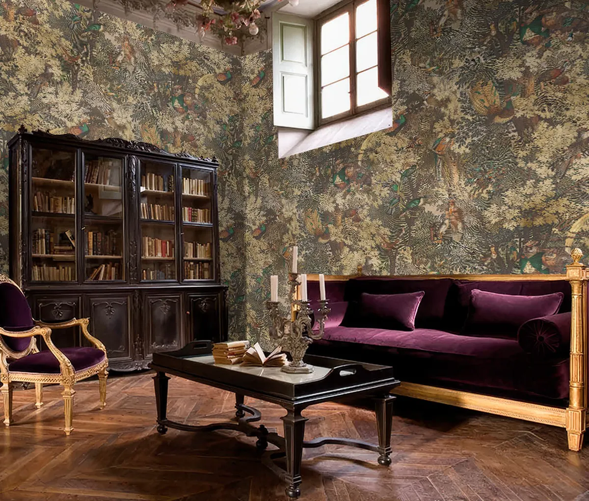 Bird and woodland wallpaper behind a plum sofa beside a bookcase