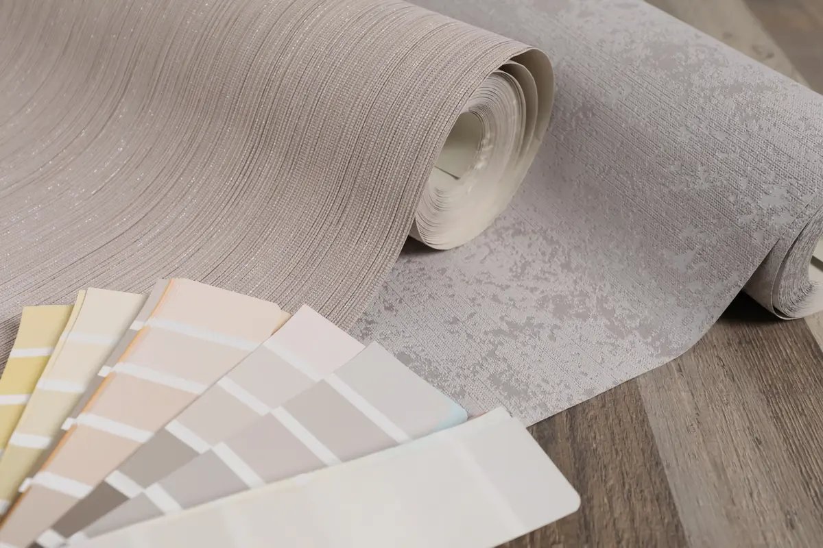 Wallpaper rolls and paint color samples arranged for comparison